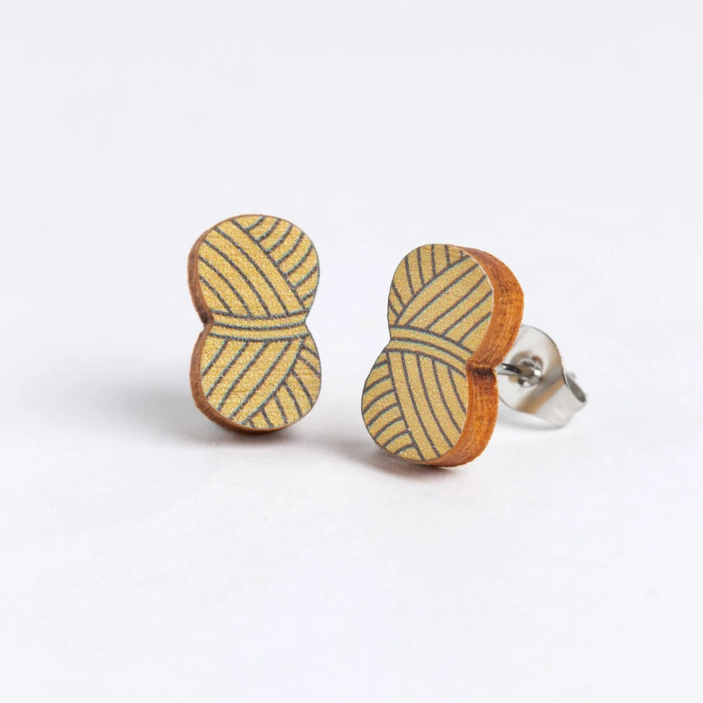 A pair of wooden stud earrings shaped like yarn, featuring a yellow and brown striped pattern on the front and a silver-tone post on the back, set against a plain white background.
