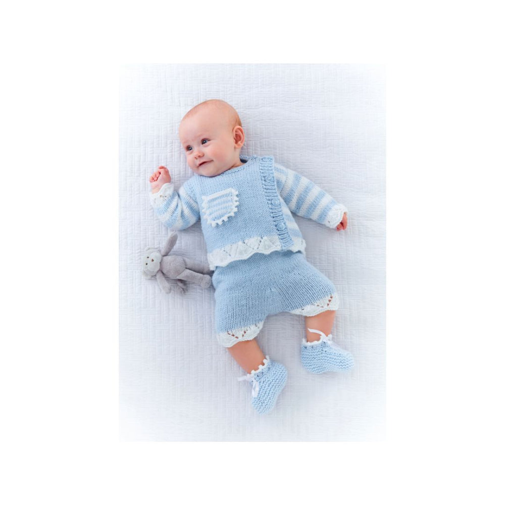 A baby lying on a white textured blanket wearing a light blue and white striped knit romper, matching skirt, and booties, with a small gray plush toy beside them.