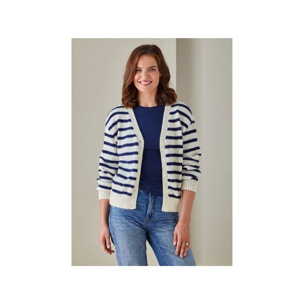 A woman modeling a navy blue and cream striped knit cardigan over a navy top and blue jeans, set against a neutral beige background.