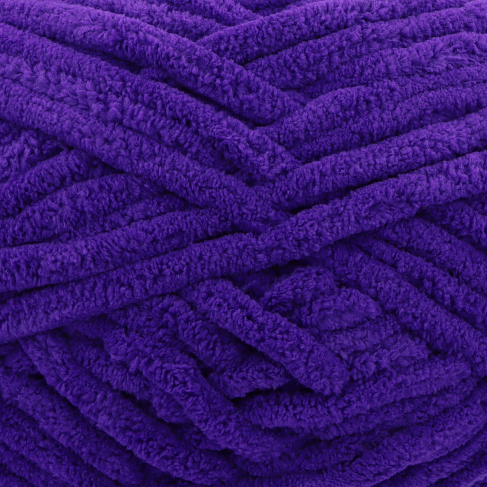 A close-up of thick, plush purple yarn strands arranged in a textured pattern.