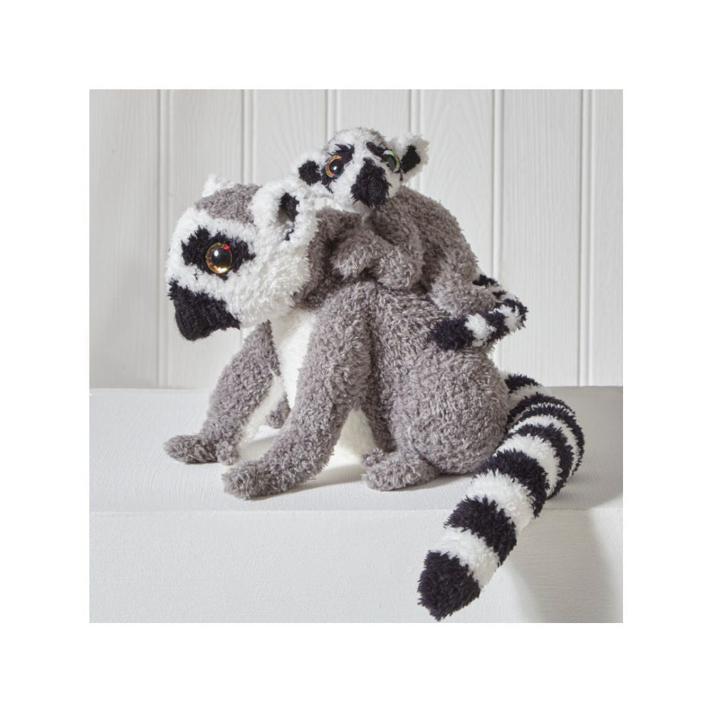 A plush toy set featuring two small ring-tailed lemurs, one larger sitting lemur and one smaller one perched on its back, both with gray, black, and white fur and realistic eyes, displayed on a white surface against a white paneled background.