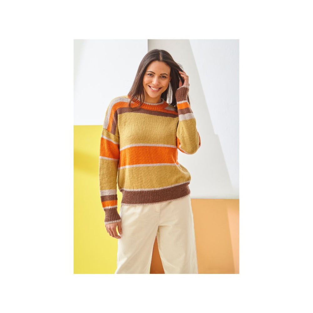 A woman wearing a striped knit sweater with horizontal bands of mustard yellow, orange, and brown, paired with cream-colored pants, standing against a modern geometric studio background of white, yellow, and orange.