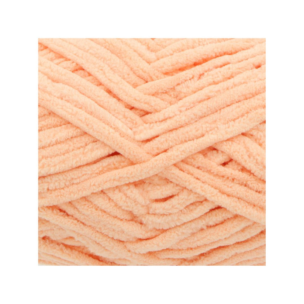 A close-up of peach-coloured chenille yarn strands arranged in a textured crisscross pattern on a white background.