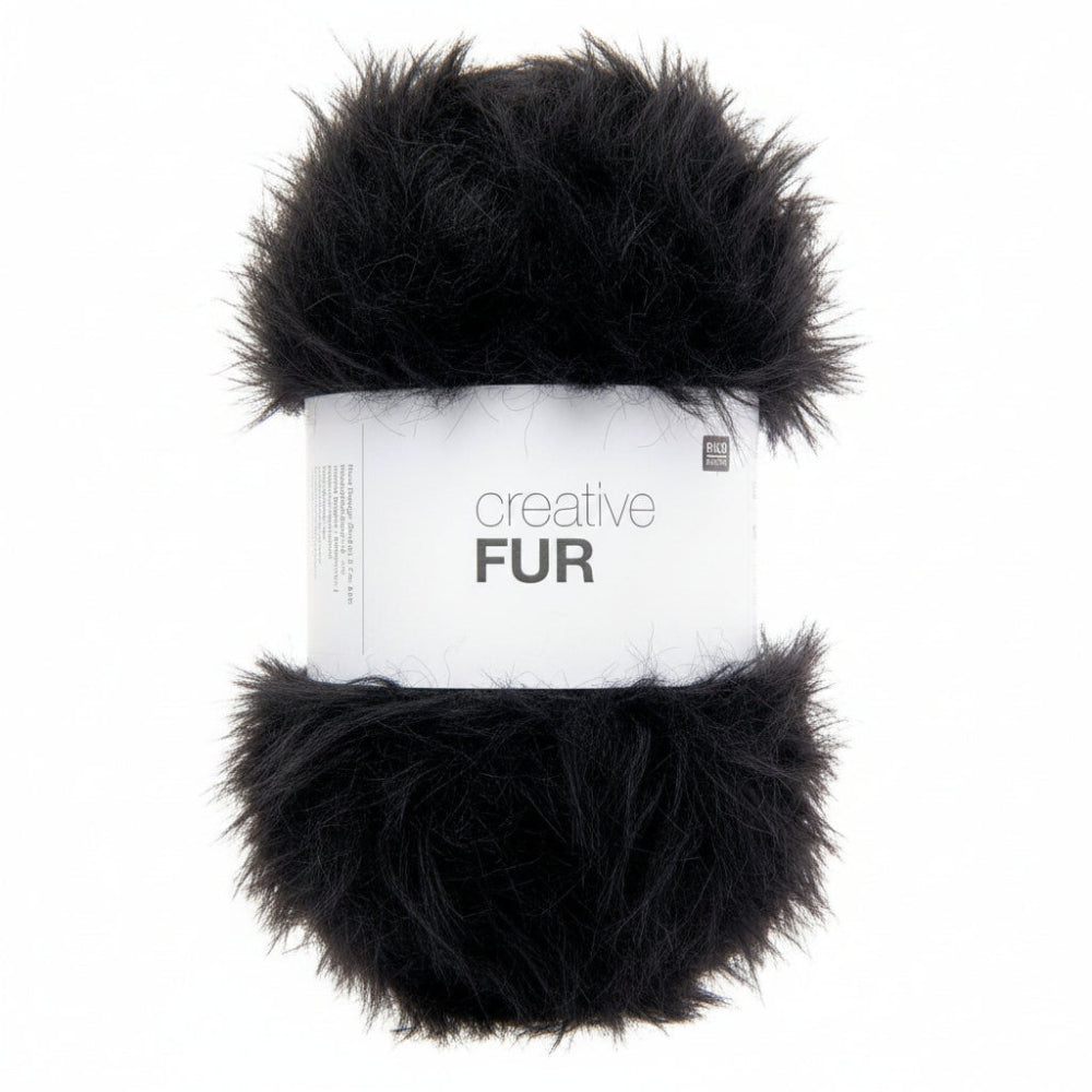 A skein of black faux fur yarn wrapped in a white paper band labeled 'creative FUR' against a plain white background.