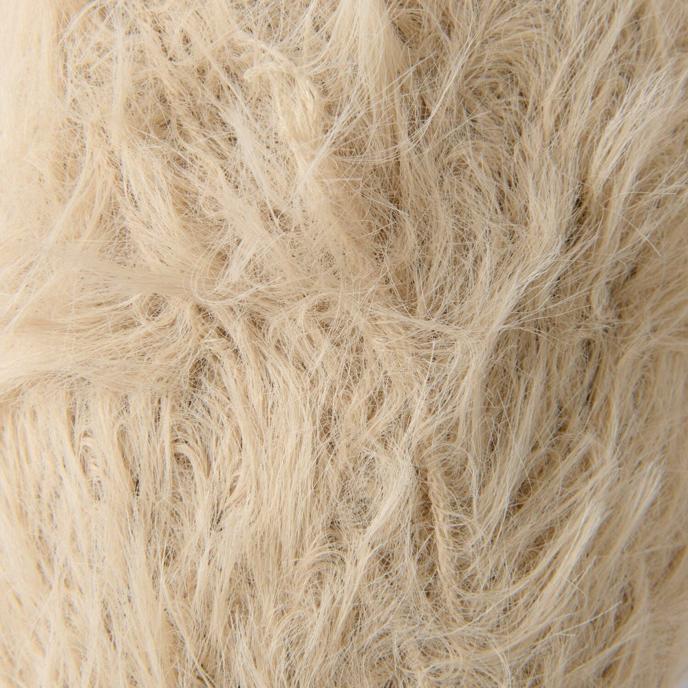 A close-up texture shot of shaggy, long-pile faux fur fabric in a light cream or beige color.