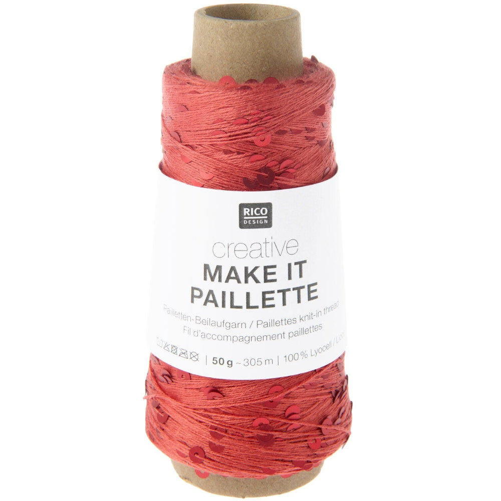 A spool of Rico Design creative 'Make It Paillette' yarn in a coral pink shade, wound on a brown cardboard core with a white paper label.