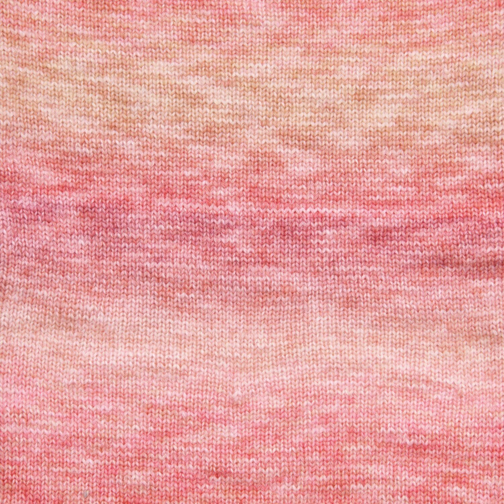 A close-up of a textured knit fabric with a marled gradient pattern transitioning from peach and beige at the top to soft pink at the bottom.