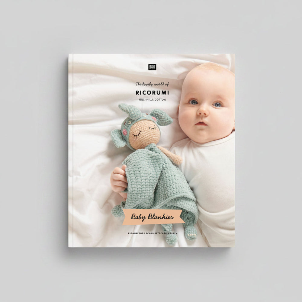 Baby holding a green crochet blanket with 'Ricorumi' branding