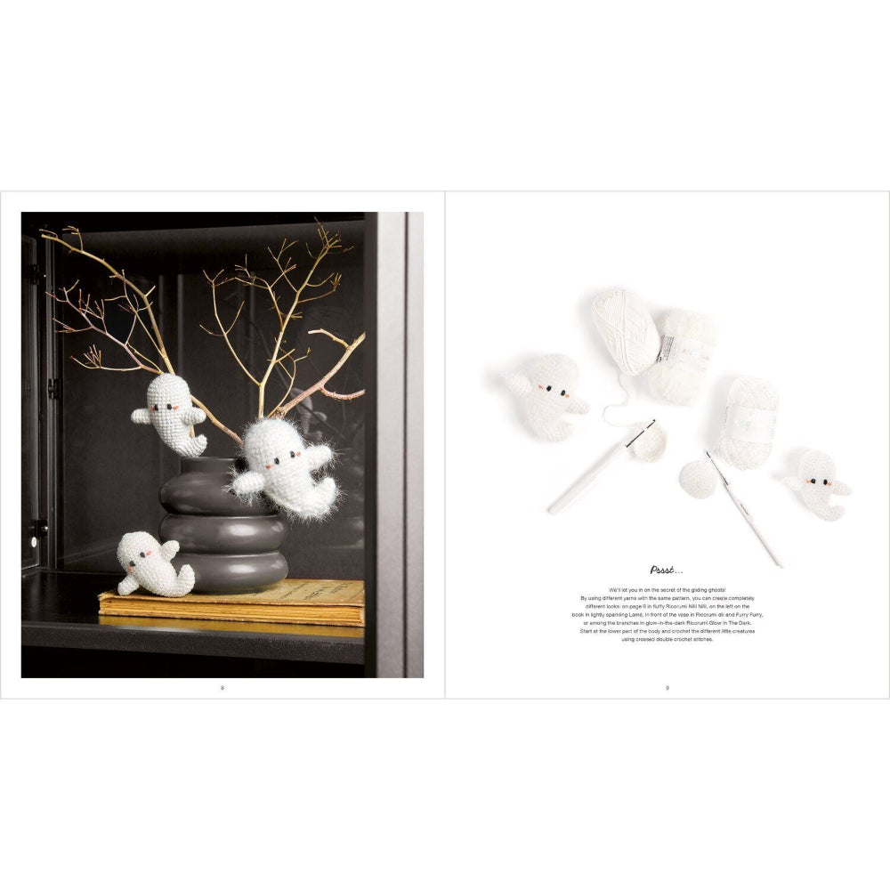 A two-page crochet pattern booklet spread showing finished white ghost-shaped plush toys and yarn needles, alongside a photo of the ghost toys displayed in a dark cabinet. The left page includes decorative branches and a small book, while the right page has a white background