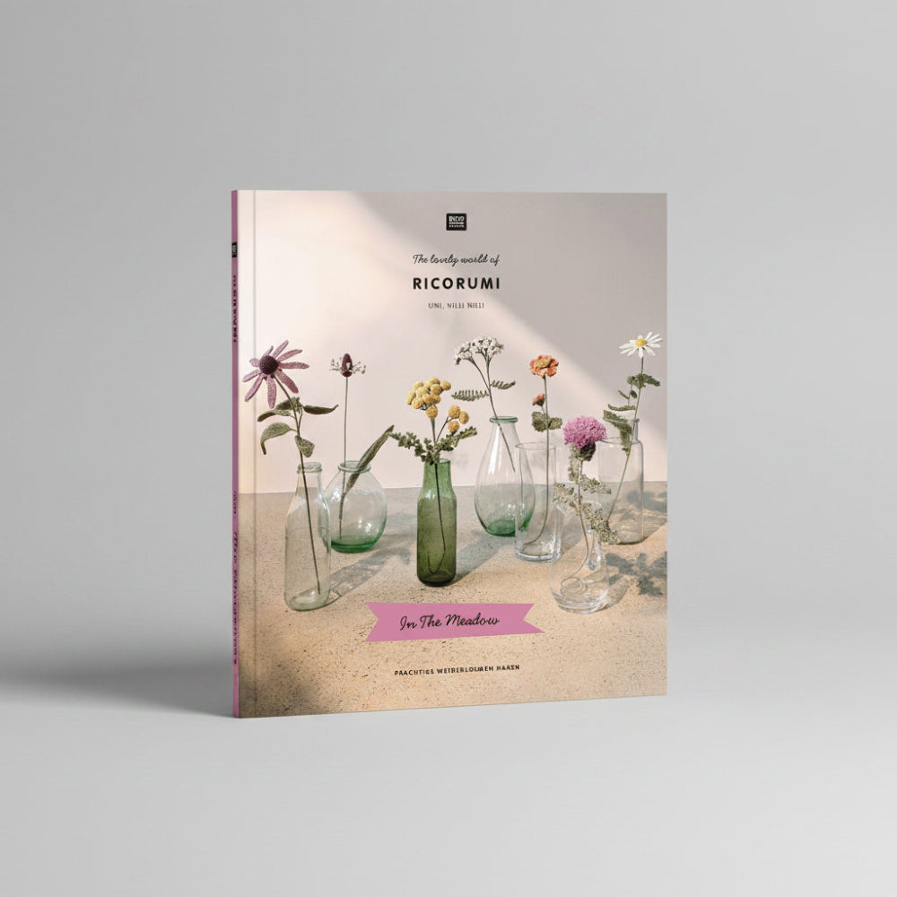 A book cover titled "The lovely world of RICORUMI" featuring several glass vases with dried and fresh flowers on a tabletop against a soft beige background. The cover includes the publisher mark "BLOOM" at the top and a pink banner reading "In The Meadow" near the bottom.
