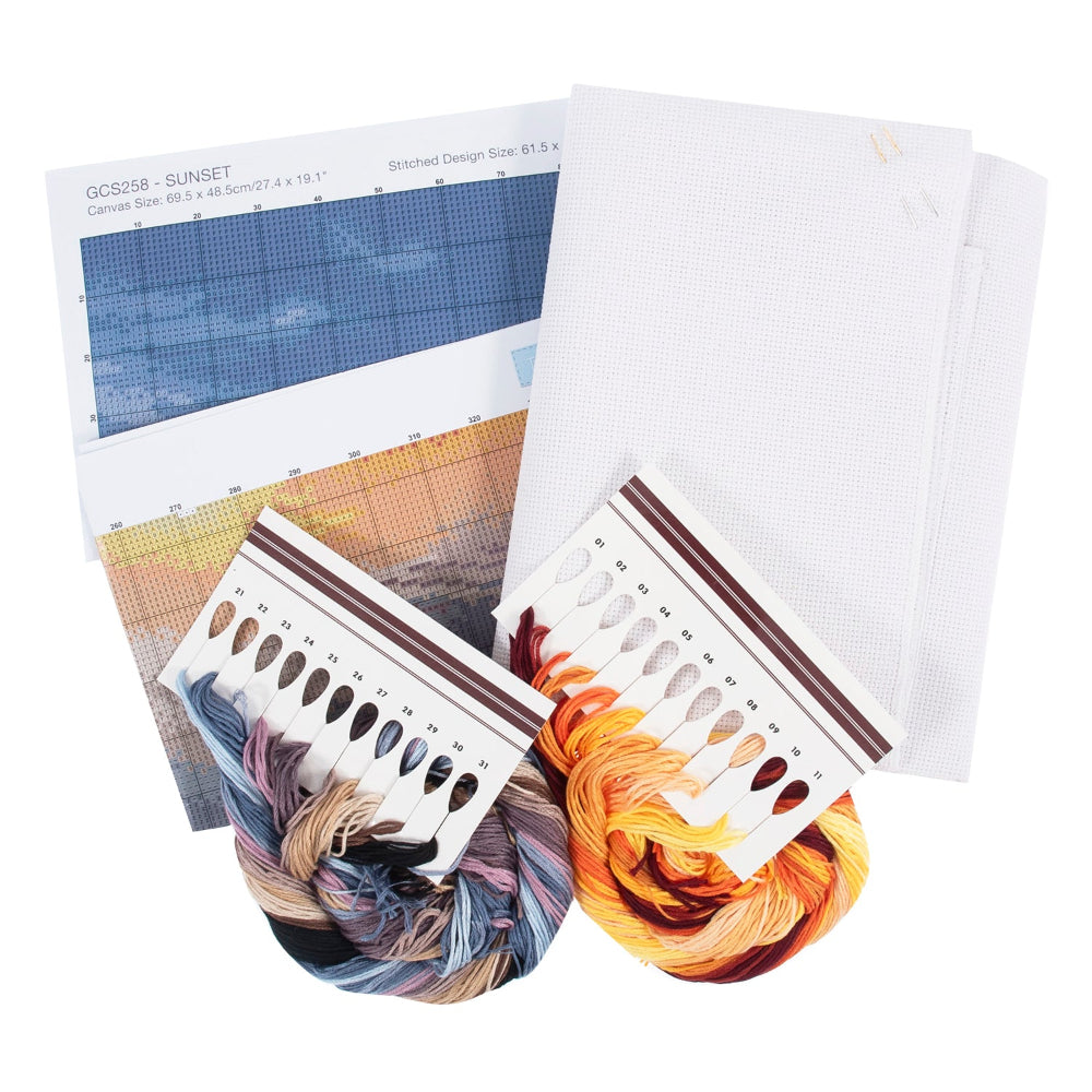 A needlework kit set including a white canvas fabric, a printed design sheet labeled GC2358 - SUNSET, two skeins of embroidery floss in blue-purple and orange-brown, and two colour swatch cards on a white background.
