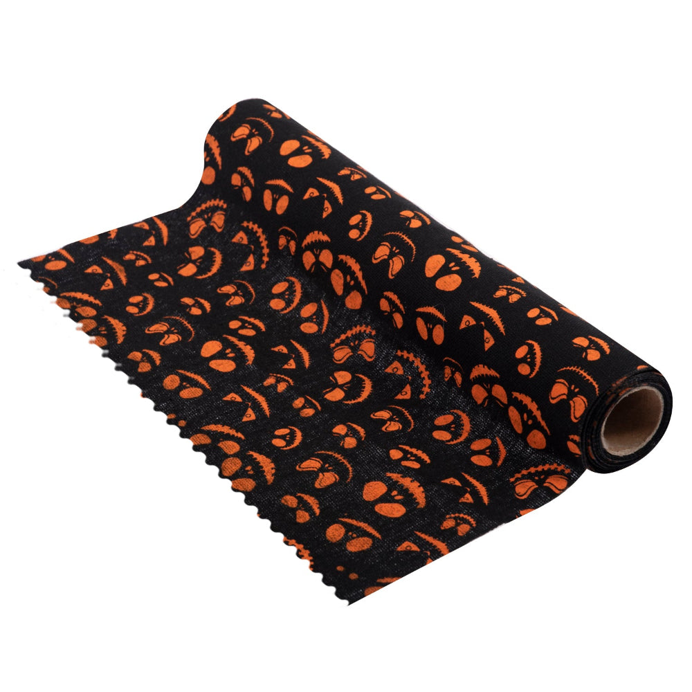 A roll of black fabric with an orange pumpkin jack-o'-lantern pattern, shown partially unrolled on a white background.