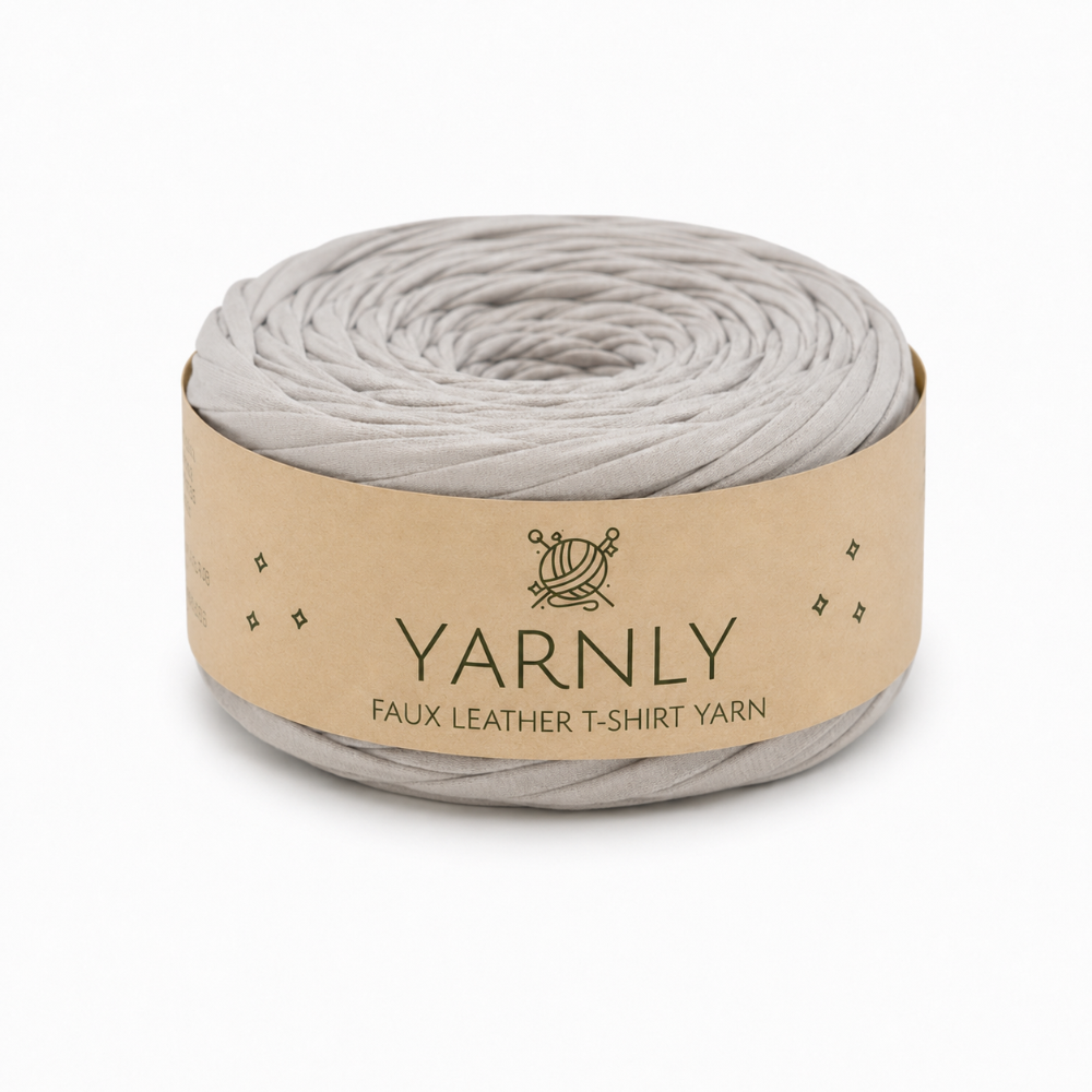 A roll of Yarnly faux leather T-shirt yarn in a light gray color, wrapped in a kraft paper band with the brand name 'YARNLY' printed on it, set against a plain white background.