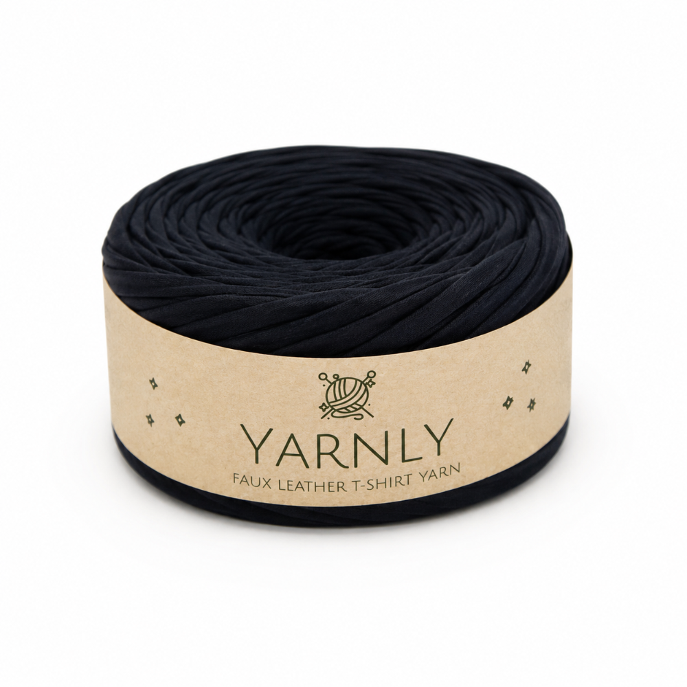 A roll of black faux leather t-shirt yarn wrapped in a beige paper band labeled 'YARNLY'.