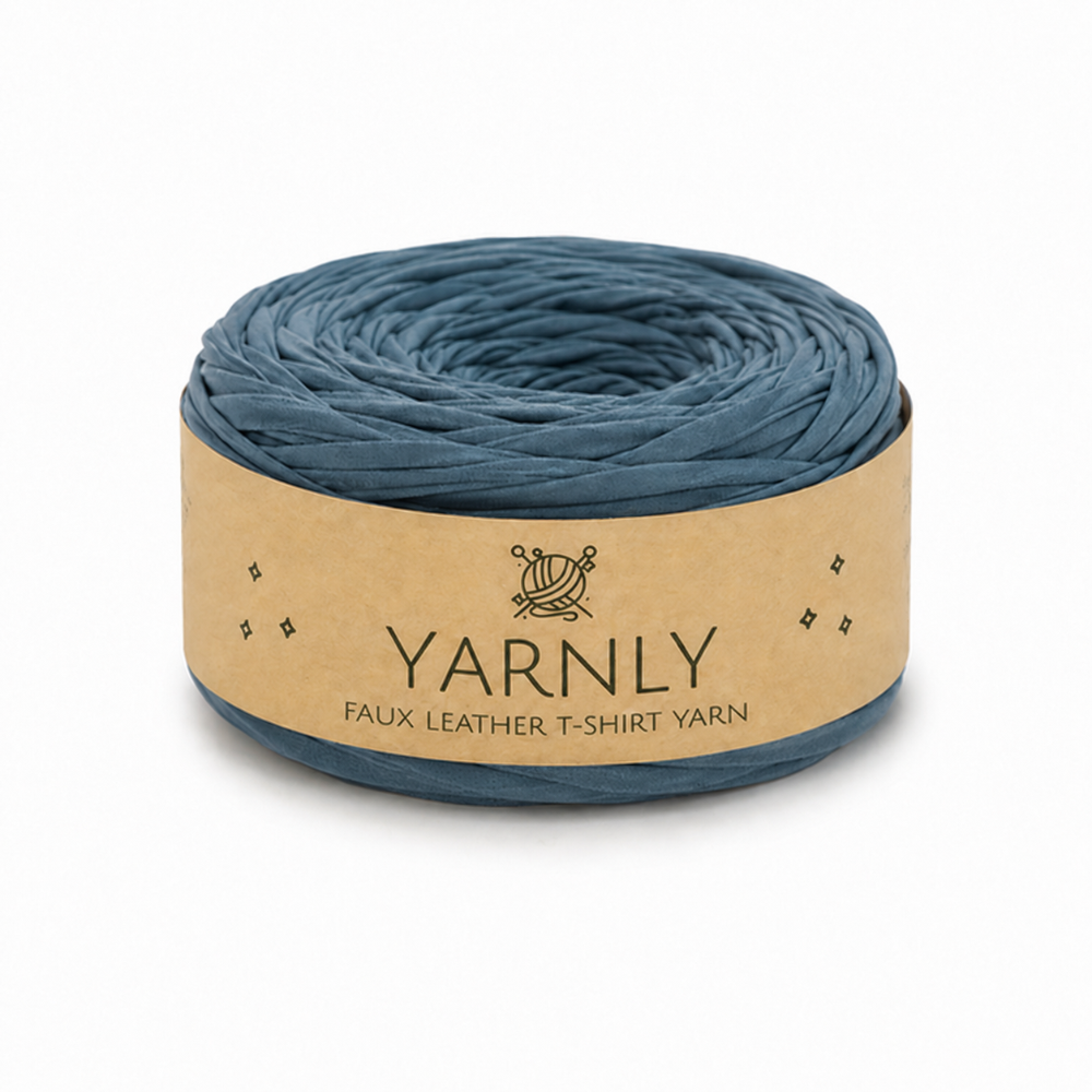 A roll of Yarnly faux leather t-shirt yarn in a muted slate blue color, wrapped in a kraft paper band with the brand name clearly visible.