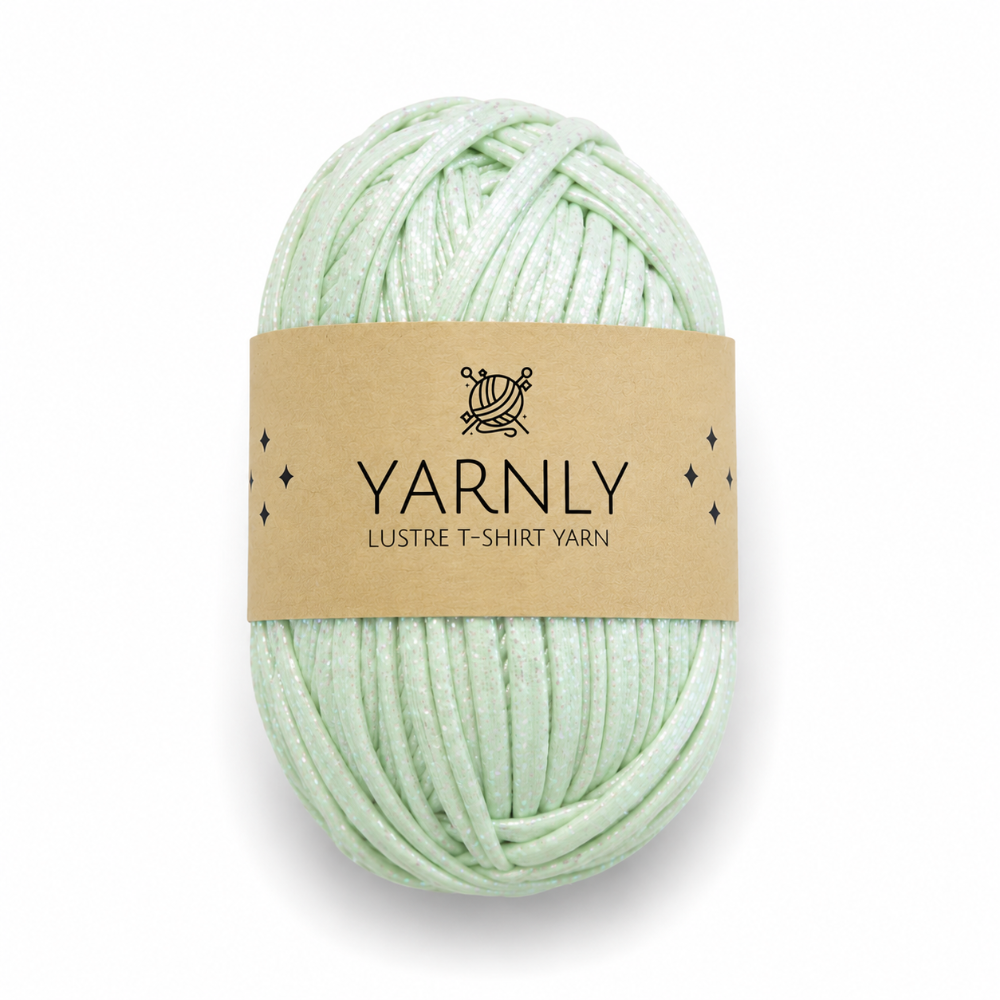 A ball of pale mint green yarn wrapped with a brown paper label that reads 'YARNLY LUSTRE T-SHIRT YARN' on a white background.