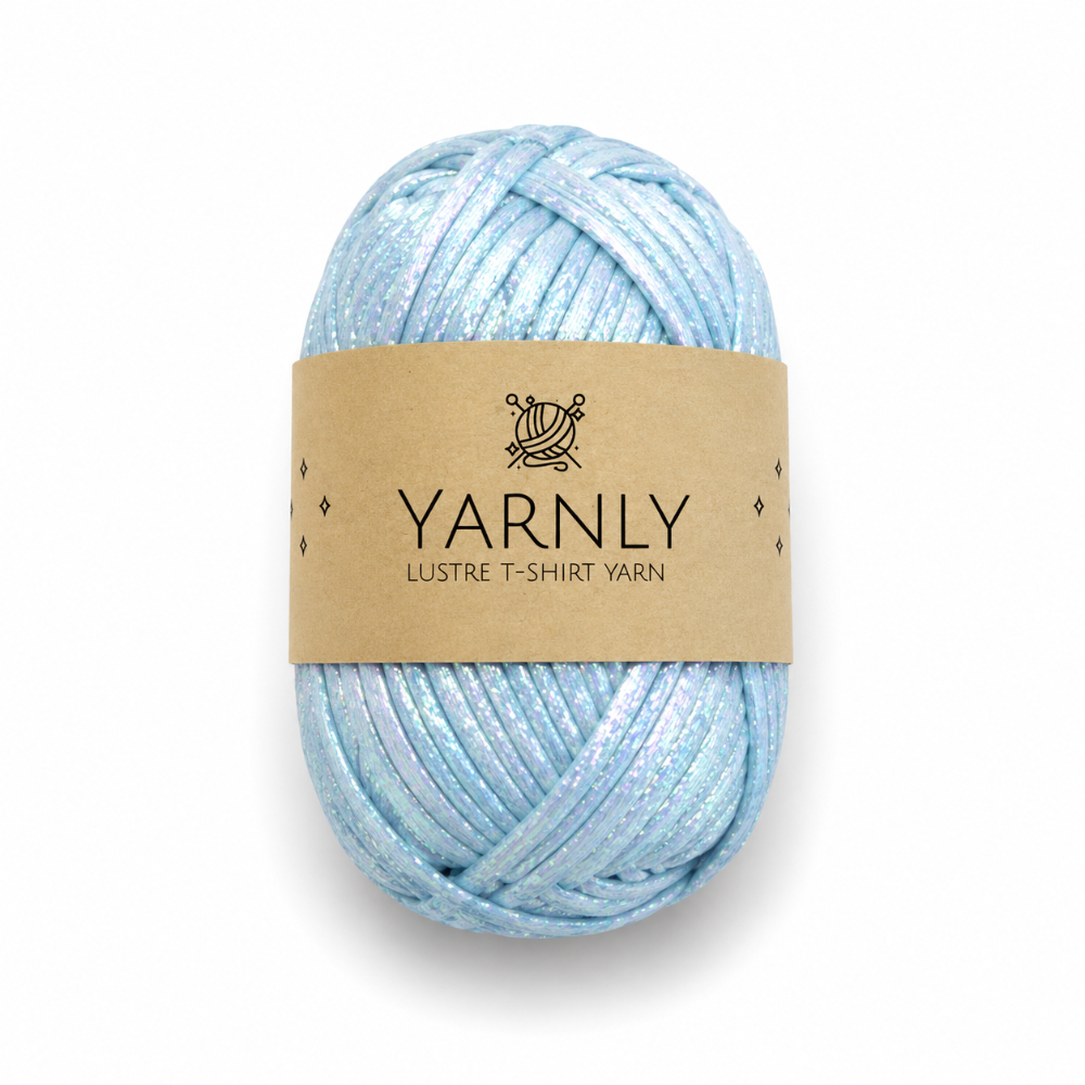 A skein of light blue glittery t-shirt yarn with a brown paper label reading 'YARNLY LUSTRE T-SHIRT YARN' on a white background.