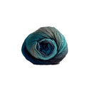 A single ball of variegated yarn with a colour-changing gradient from grey and teal to deep blue, isolated on a solid white background.