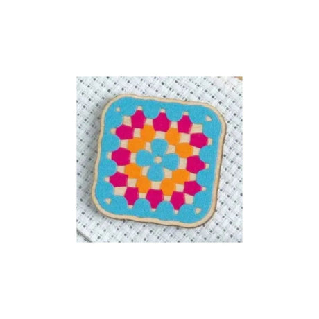 A square fabric patch with rounded corners featuring a colorful geometric granny square pattern, displayed on a white textured mesh background.