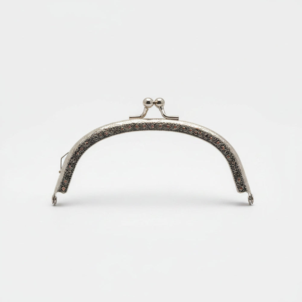 A silver metal bag clasp with clear rhinestones, presented in its pink retail packaging by Hemline.