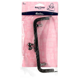 A Hemline brand black glittery bag clasp tool with silver metal tips, packaged in a clear plastic sleeve on a pink cardboard backing.