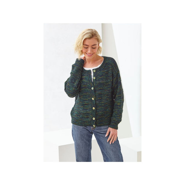 A woman wearing a dark green and blue textured knit cardigan with gold buttons, paired with blue jeans, standing against a white geometric studio background.