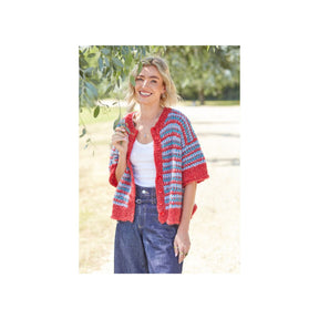 A woman standing outdoors in front of a tree wearing a colourful knit cardigan with red, blue, and white stripes, a white tank top, and dark blue jeans.