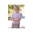 A woman wearing a pink and white patterned knit sweater with puff sleeves and a ribbed hem, paired with brown trousers, standing outdoors with her arms crossed.