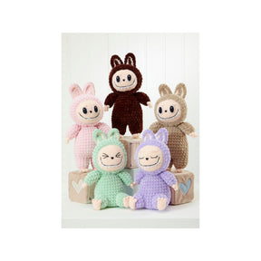 Five crocheted plush toy characters arranged on stacked blocks against a white paneled background. The characters wear pastel-coloured hooded suits in pink, brown, beige, mint green, and lavender, with embroidered faces and simple stitched details.