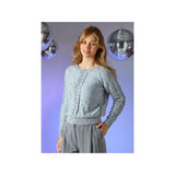 A woman modeling a light blue cable-knit sweater with colourful sequins, paired with grey striped pants, set against a purple background with hanging disco balls.