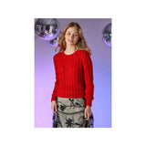 A woman modeling a bright red lace-knit sweater with sequined details, paired with a patterned skirt, set against a purple-lit background with disco ball props.