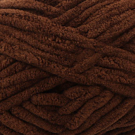 A close-up of thick, plush yarn in a rich dark brown color, showing its soft, fuzzy texture.