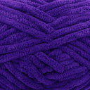 A close-up of thick, plush purple yarn strands arranged in a textured pattern.
