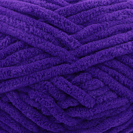 A close-up of thick, plush purple yarn strands arranged in a textured pattern.