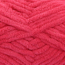 A close-up of bright pink fuzzy chenille yarn wound into thick skeins, showing the soft textured loops of the fabric.
