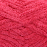 A close-up of bright pink fuzzy chenille yarn wound into thick skeins, showing the soft textured loops of the fabric.