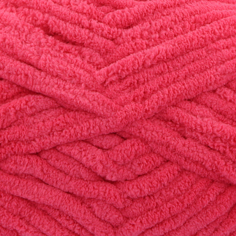 A close-up of bright pink fuzzy chenille yarn wound into thick skeins, showing the soft textured loops of the fabric.