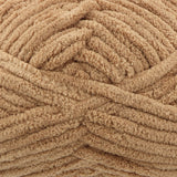 A close-up of thick, plush chenille yarn in a warm tan or light brown colour, showing the soft, looped texture of the material.