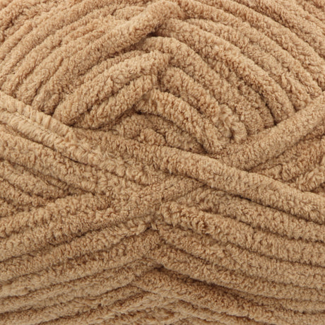 A close-up of thick, plush chenille yarn in a warm tan or light brown colour, showing the soft, looped texture of the material.