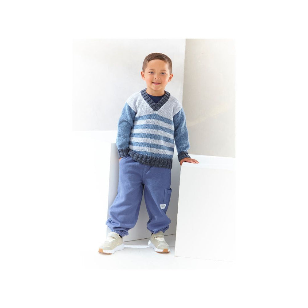 A young boy wearing a blue and white striped knit sweater, blue trousers, and white sneakers, standing in a bright white studio setting.