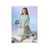 A young girl stands in a studio wearing a light mint green knit cardigan over a matching pleated skirt. She is posed among several large silver disco balls against a soft blue-to-lavender gradient background.