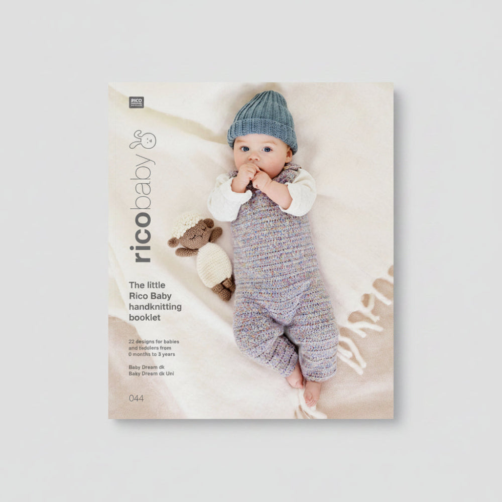 Rico Baby handknitting booklet cover featuring a baby lying on a soft cream blanket, wearing a knitted blue hat and a multicolored knitted romper, with a small knitted sheep toy beside them. The left side includes the title 'The little Rico Baby handknitting booklet' and the RICO BABY logo.