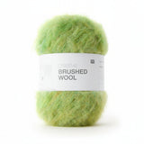 A ball of fluffy lime green yarn wrapped in a white paper band labeled 'creative BRUSHED WOOL' on a plain white background.