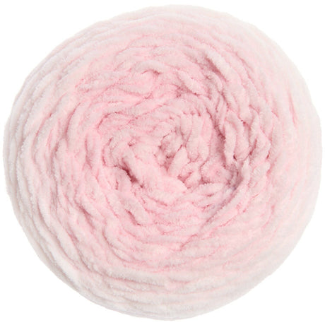 A top-down view of a fluffy, chunky circular skein of yarn in a soft light pink color, isolated on a white background.