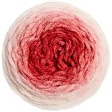 A top-down view of a round ball of plush, fuzzy yarn with a color gradient transitioning from off-white at the outer edges to light pink and deep red in the center, isolated on a white background.