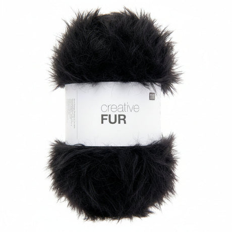 A skein of black faux fur yarn wrapped in a white paper band labeled 'creative FUR' against a plain white background.