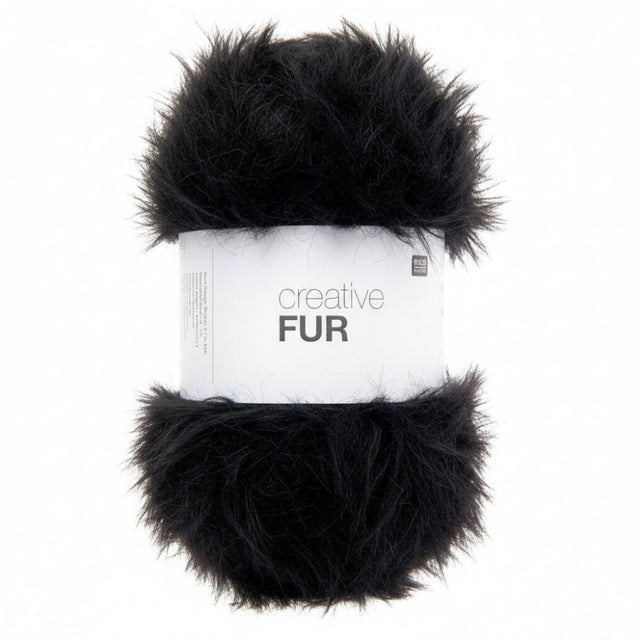 A skein of black faux fur yarn wrapped in a white paper band labeled 'creative FUR' against a plain white background.
