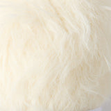 A close-up of fluffy faux fur fabric in a warm off-white or cream color.