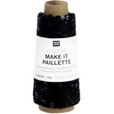 A spool of black knit thread with a white paper label reading 'RICO DESIGN creative MAKE IT PAILLETTE' on a plain white background.