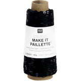 A spool of black knit thread with a white paper label reading 'RICO DESIGN creative MAKE IT PAILLETTE' on a plain white background.